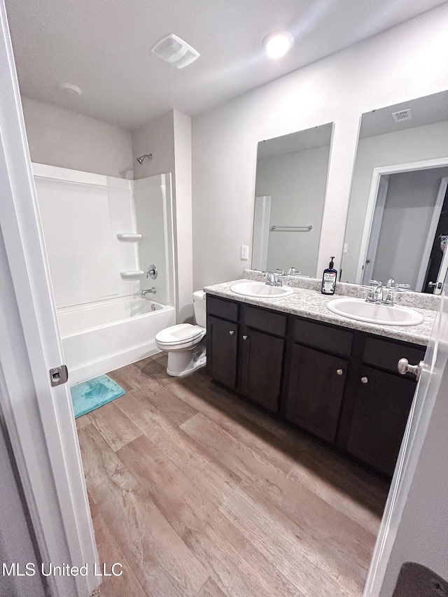 bathroom with a sink, shower / bathing tub combination, wood finished floors, and double vanity