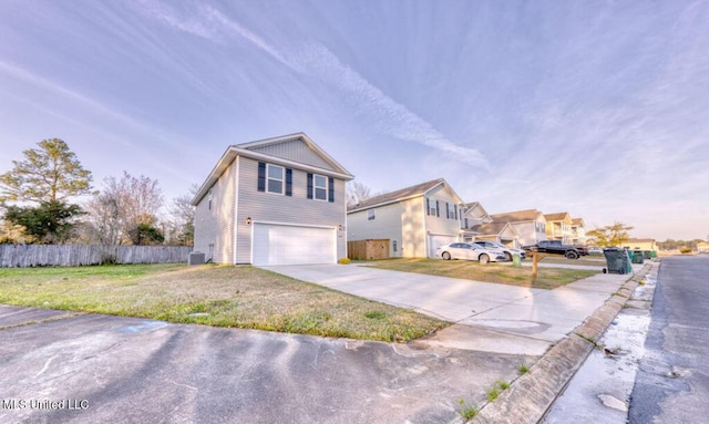 view of front of home with a garage, a front lawn, driveway, and fence