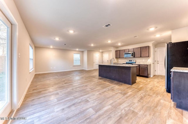 kitchen with visible vents, light wood-style flooring, stainless steel appliances, light countertops, and open floor plan