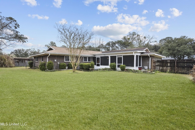 back of property featuring a yard, fence, a sunroom, and brick siding