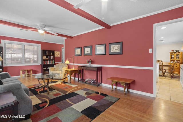 living room with a textured ceiling, wood finished floors, a ceiling fan, baseboards, and crown molding