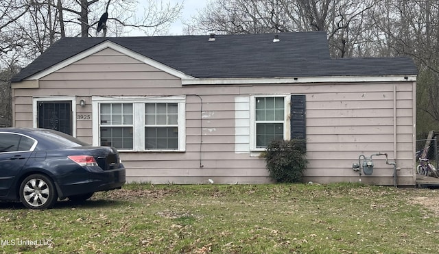 exterior space featuring a front lawn and a shingled roof