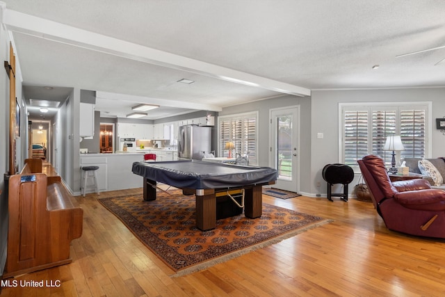 recreation room featuring beamed ceiling, light hardwood / wood-style flooring, a textured ceiling, and billiards