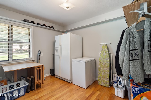 clothes washing area with light hardwood / wood-style flooring