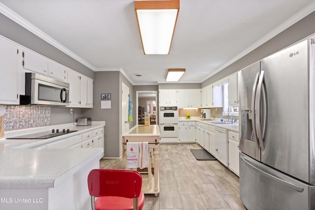 kitchen featuring a breakfast bar area, sink, appliances with stainless steel finishes, and white cabinets