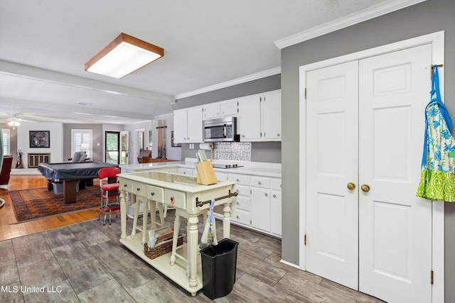 kitchen with decorative backsplash, hardwood / wood-style flooring, ornamental molding, billiards, and white cabinets