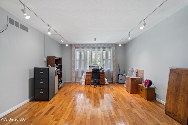 unfurnished office featuring track lighting, light hardwood / wood-style flooring, and a textured ceiling