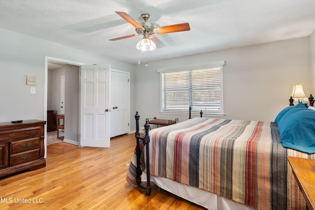 bedroom with a textured ceiling, light wood-type flooring, and ceiling fan