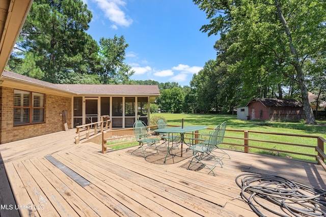 wooden deck with a shed, a lawn, and a sunroom