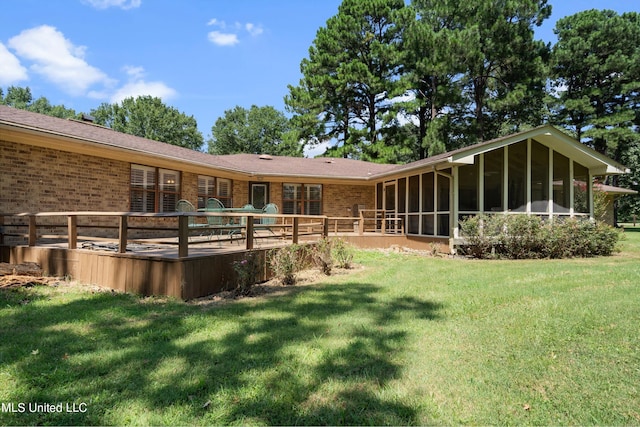 rear view of property featuring a deck, a lawn, and a sunroom