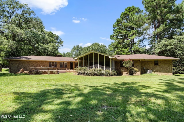 rear view of property featuring central AC, a lawn, and a sunroom