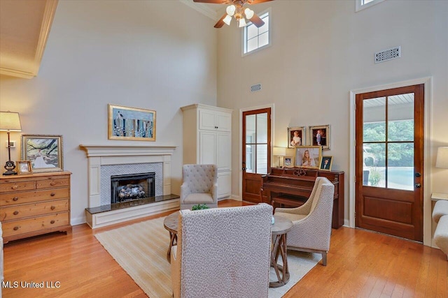 210 Planters Grv, Brandon, MS 39047 - living room featuring light wood-style floors, ceiling fan, crown molding, a fireplace with raised hearth, and a towering ceiling