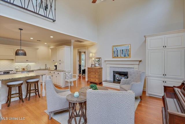 210 Planters Grv, Brandon, MS 39047 - living room with light wood-type flooring, ornamental molding, a fireplace with raised hearth, a towering ceiling, and a ceiling fan