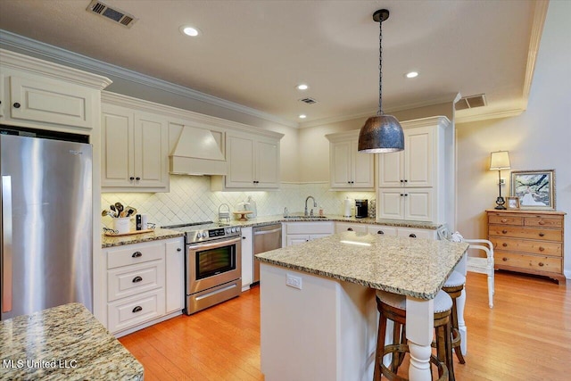 210 Planters Grv, Brandon, MS 39047 - kitchen featuring appliances with stainless steel finishes, premium range hood, a sink, decorative light fixtures, and ornamental molding
