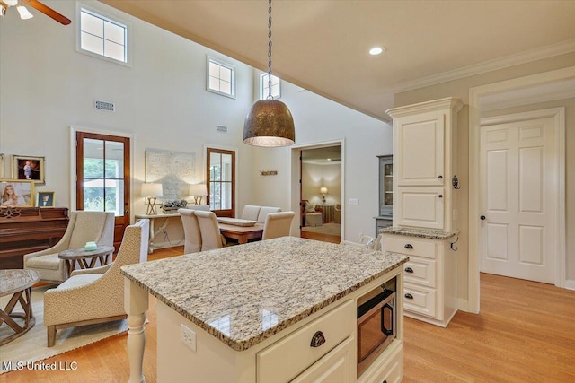 210 Planters Grv, Brandon, MS 39047 - kitchen with stainless steel microwave, open floor plan, light stone countertops, plenty of natural light, and crown molding