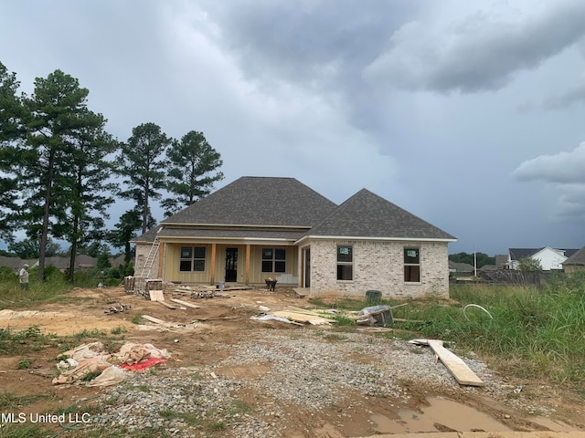 rear view of property with brick siding and roof with shingles