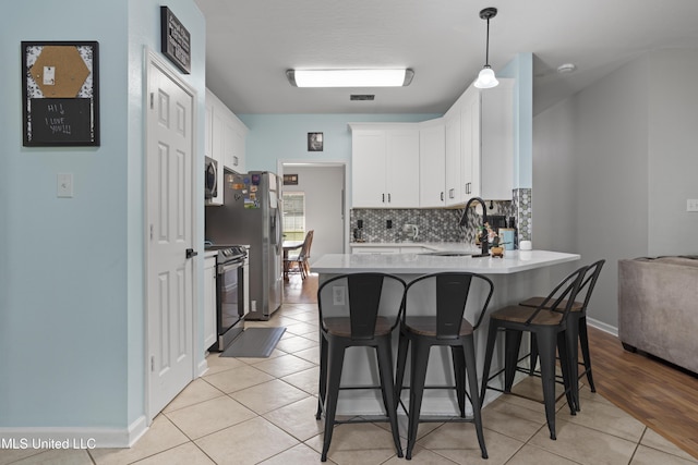 6507 Shoshonee Dr, Ocean Springs, MS 39564 - kitchen featuring black electric range, a sink, stainless steel microwave, a peninsula, and a breakfast bar