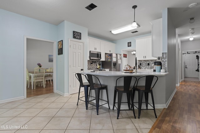 6507 Shoshonee Dr, Ocean Springs, MS 39564 - kitchen with appliances with stainless steel finishes, a peninsula, backsplash, white cabinets, and a breakfast bar