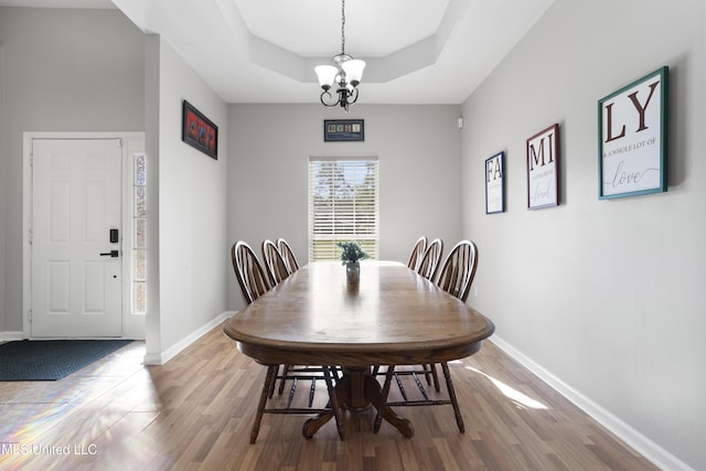 6507 Shoshonee Dr, Ocean Springs, MS 39564 - dining room featuring a chandelier, wood finished floors, a raised ceiling, and baseboards