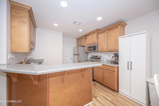 18108 Steamer Way, Gulfport, MS 39503 - kitchen with stainless steel appliances, a peninsula, a sink, light wood-type flooring, and a kitchen breakfast bar