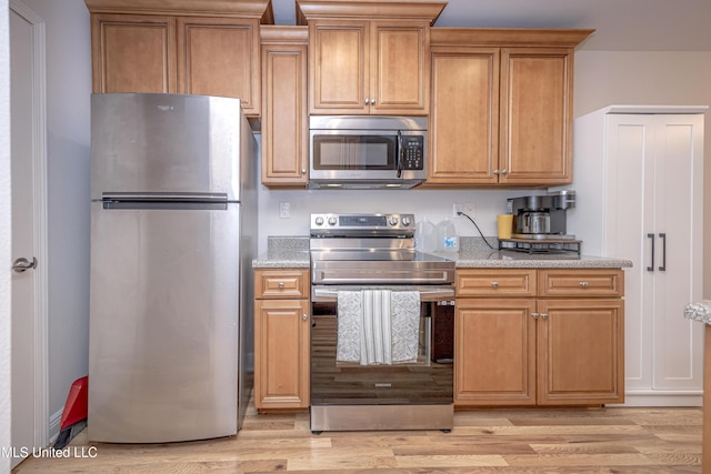 18108 Steamer Way, Gulfport, MS 39503 - kitchen featuring appliances with stainless steel finishes, light wood finished floors, light stone counters, and brown cabinets