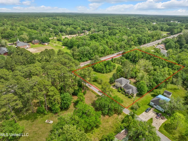aerial view of property and surrounding area featuring a heavily wooded area and property boundaries highlighted