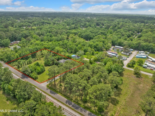 aerial view of property and surrounding area featuring a heavily wooded area and property parcel outlined