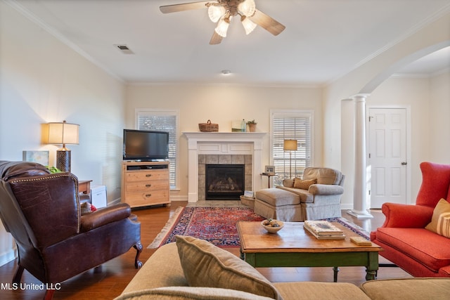 living room with ceiling fan, decorative columns, crown molding, hardwood / wood-style floors, and a fireplace