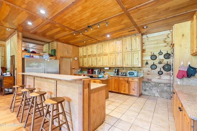 927 Abe Chapel Rd, Como, MS 38619 - kitchen with wood walls, a center island, a kitchen breakfast bar, freestanding refrigerator, and wooden ceiling