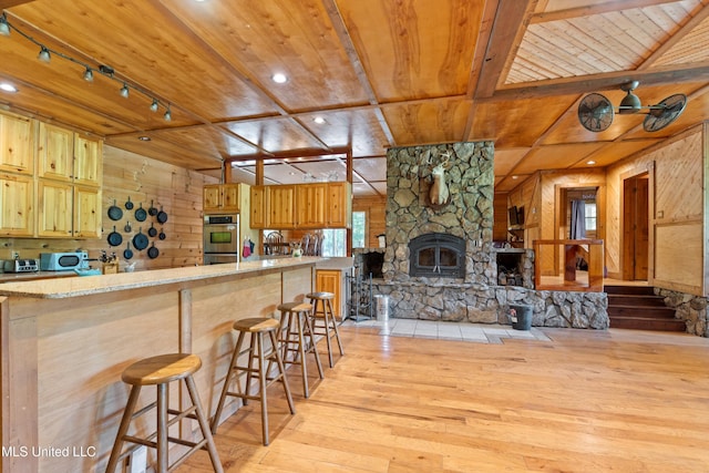 927 Abe Chapel Rd, Como, MS 38619 - kitchen featuring wood ceiling, wood walls, light wood-style floors, light countertops, and stainless steel double oven