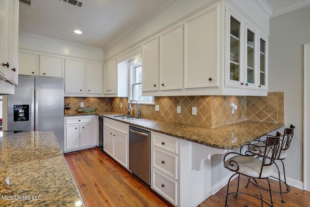 kitchen featuring a sink, crown molding, stainless steel appliances, white cabinetry, and wood-type flooring