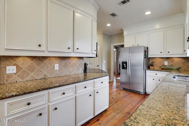 kitchen with visible vents, stainless steel fridge with ice dispenser, and white cabinetry