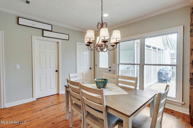 dining room with a notable chandelier, light wood-type flooring, crown molding, and baseboards