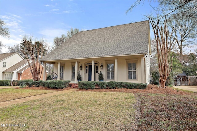 view of front of house featuring a shingled roof, a front yard, a porch, and stucco siding