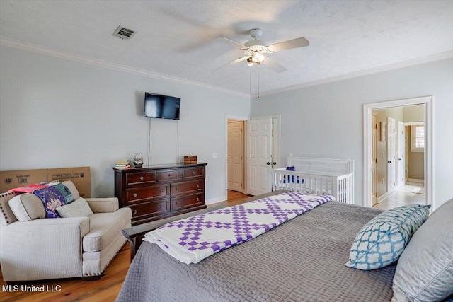 bedroom featuring wood finished floors, visible vents, and ornamental molding