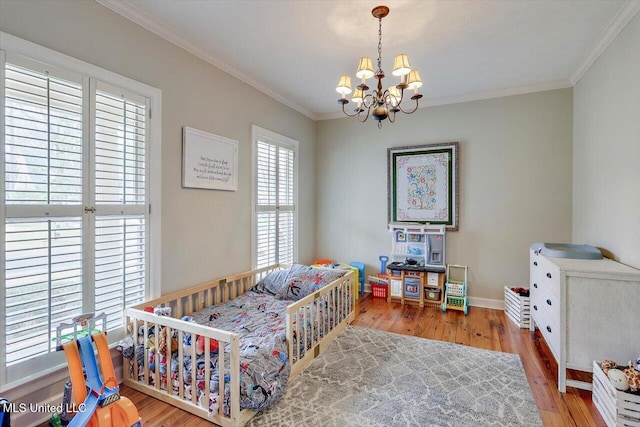 bedroom featuring a chandelier, crown molding, baseboards, and wood finished floors