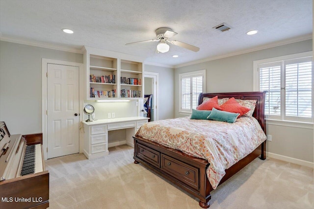 bedroom featuring light carpet, ornamental molding, a textured ceiling, built in desk, and baseboards