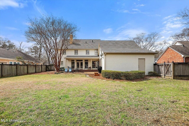 rear view of property with a yard, a fenced backyard, a chimney, and a patio area