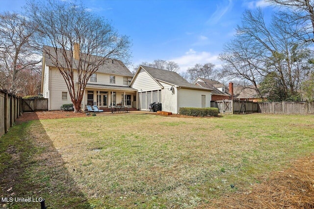 back of property featuring a yard, a fenced backyard, a chimney, and a gate