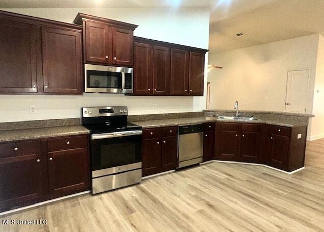 14816 Canal Crossing Blvd, Gulfport, MS 39503 - kitchen featuring stainless steel appliances, light wood-style floors, dark countertops, a peninsula, and dark brown cabinetry