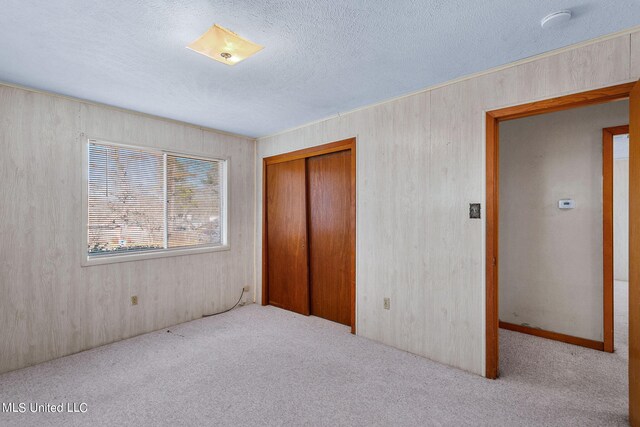 unfurnished bedroom with a textured ceiling, light colored carpet, and a closet