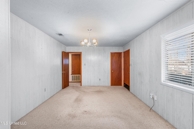 carpeted spare room featuring a chandelier