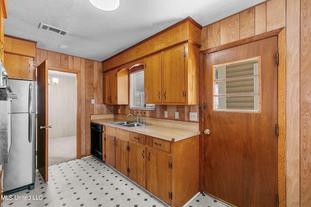 kitchen with stainless steel fridge, a textured ceiling, dishwasher, wooden walls, and sink