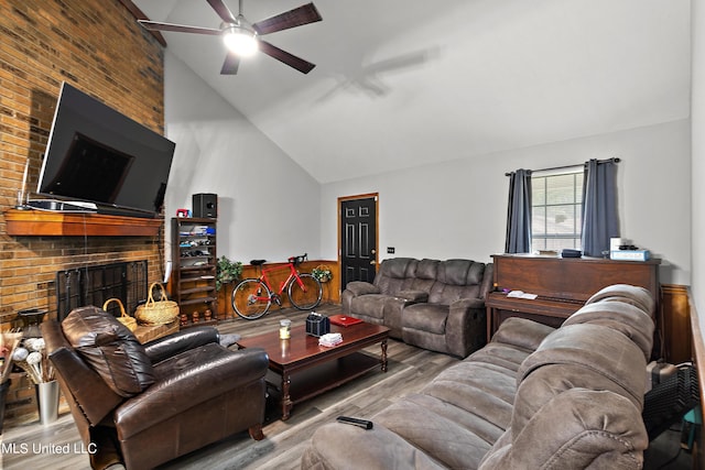 living room featuring a brick fireplace, high vaulted ceiling, light hardwood / wood-style floors, and ceiling fan