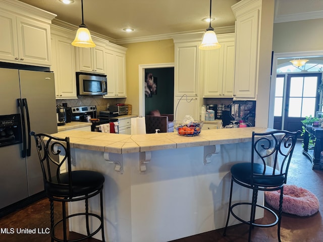 8 Audubon Pl, Natchez, MS 39120 - kitchen featuring tasteful backsplash, a breakfast bar area, tile counters, appliances with stainless steel finishes, and crown molding