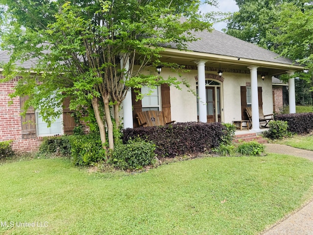 8 Audubon Pl, Natchez, MS 39120 - view of front of property with covered porch, stucco siding, a front yard, and roof with shingles