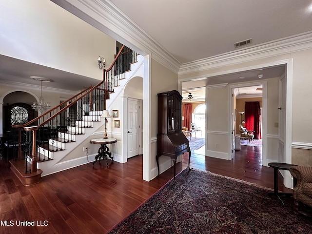 entryway featuring dark hardwood / wood-style flooring, crown molding, and an inviting chandelier