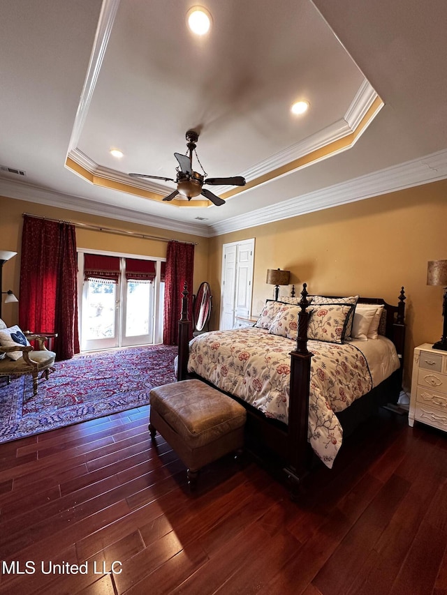 bedroom featuring dark wood-type flooring, ceiling fan, crown molding, and a raised ceiling