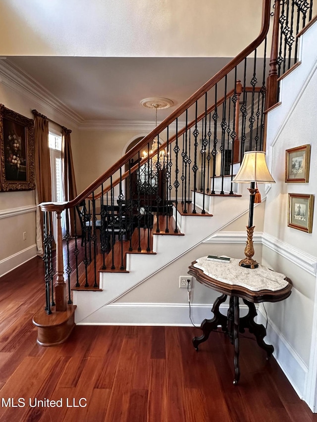 stairs with hardwood / wood-style flooring, crown molding, and a notable chandelier