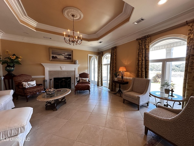 living area featuring an inviting chandelier, a raised ceiling, a tile fireplace, and light tile patterned floors